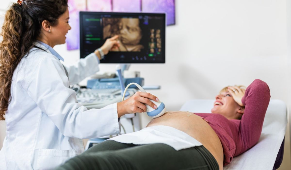 A doctor examines a pregnant woman during a routine check-up in a clinical setting.