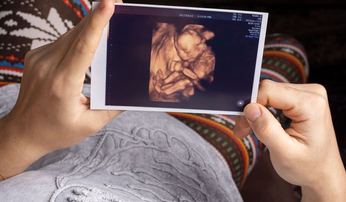 A woman examines her baby using an ultrasound machine during a prenatal check-up.